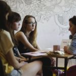 Cztery kobiety siedzące przy stole prowadzą rozmowę.